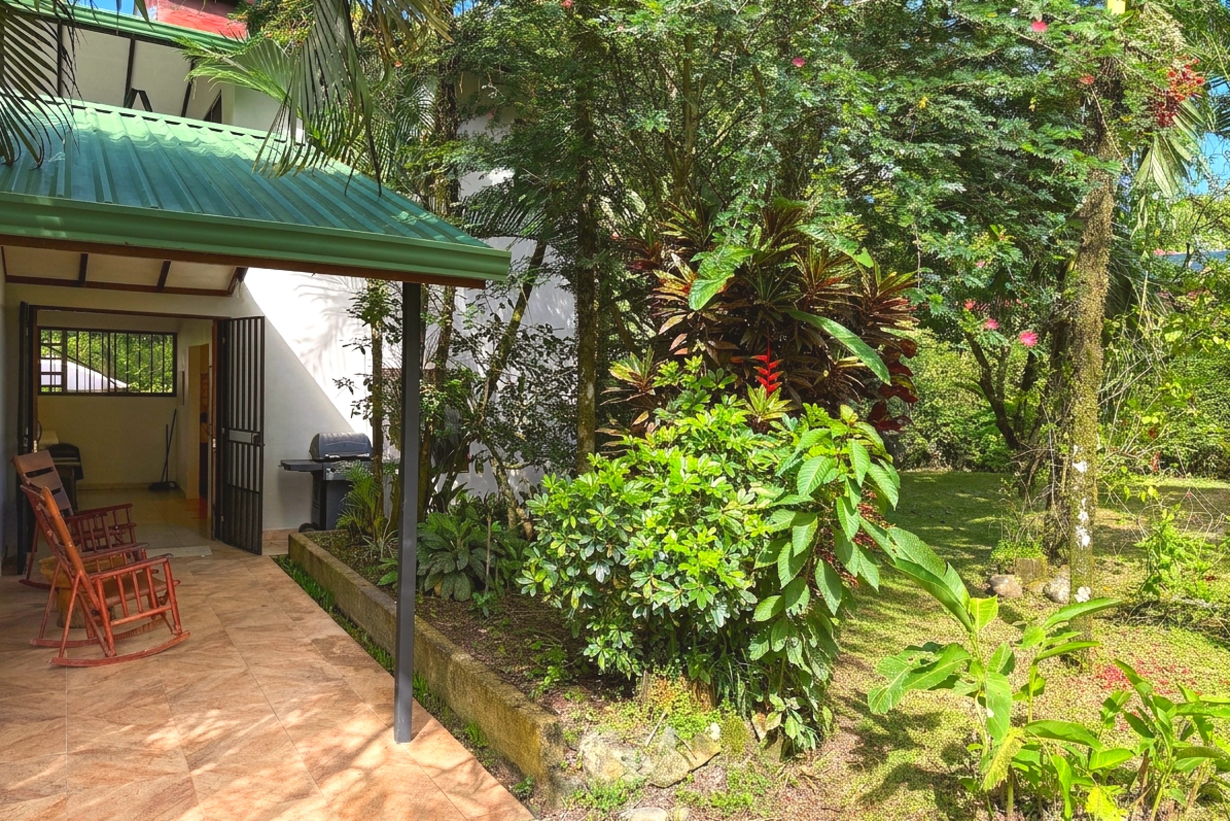 Covered Patio & Garden View Jungle Sanctuary covered patio with rocking chairs and lush garden in Ojochal, Costa Rica