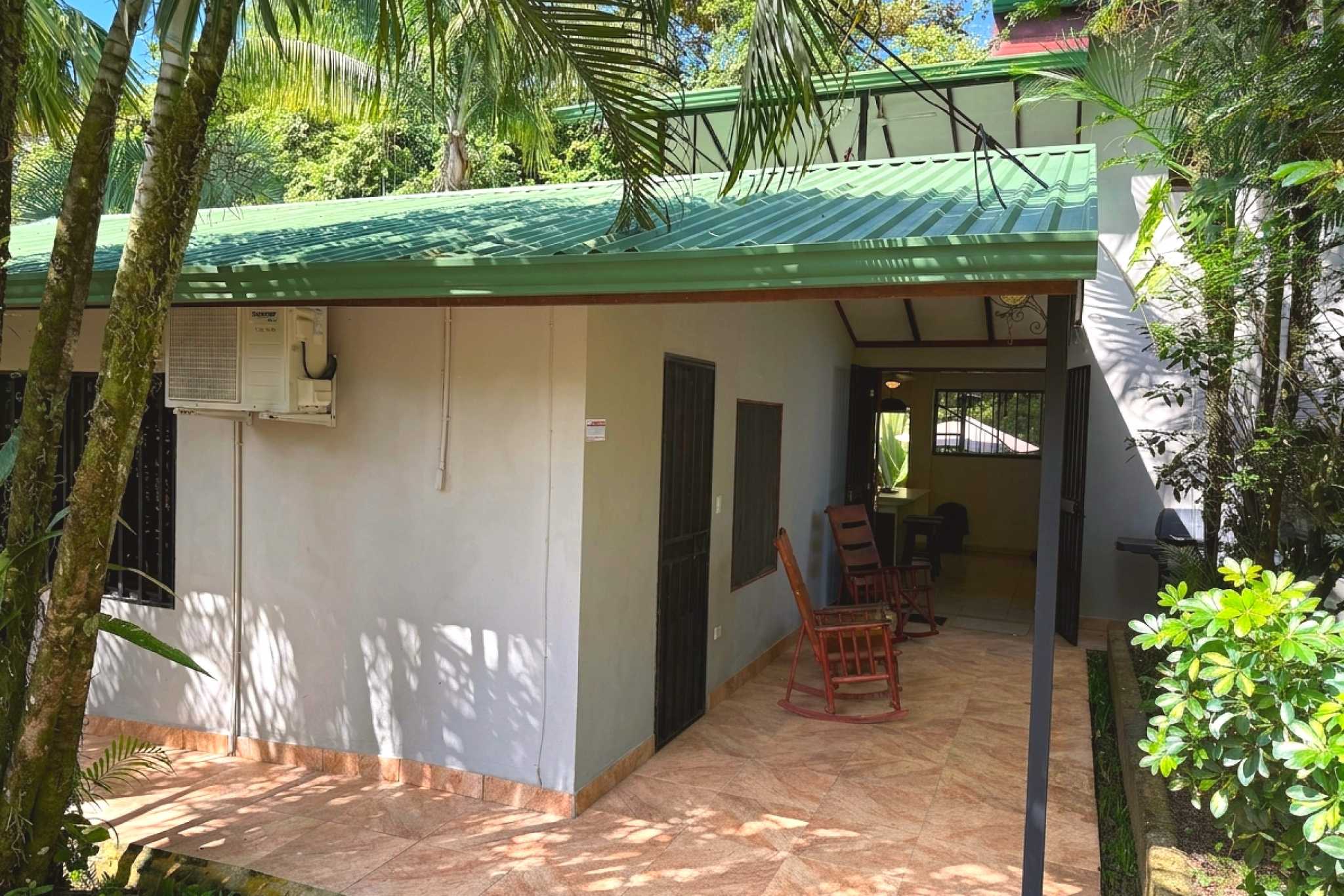 Covered Patio Entrance Jungle Sanctuary Villa green-roofed exterior with rocking chairs and covered patio in Ojochal, Costa Rica