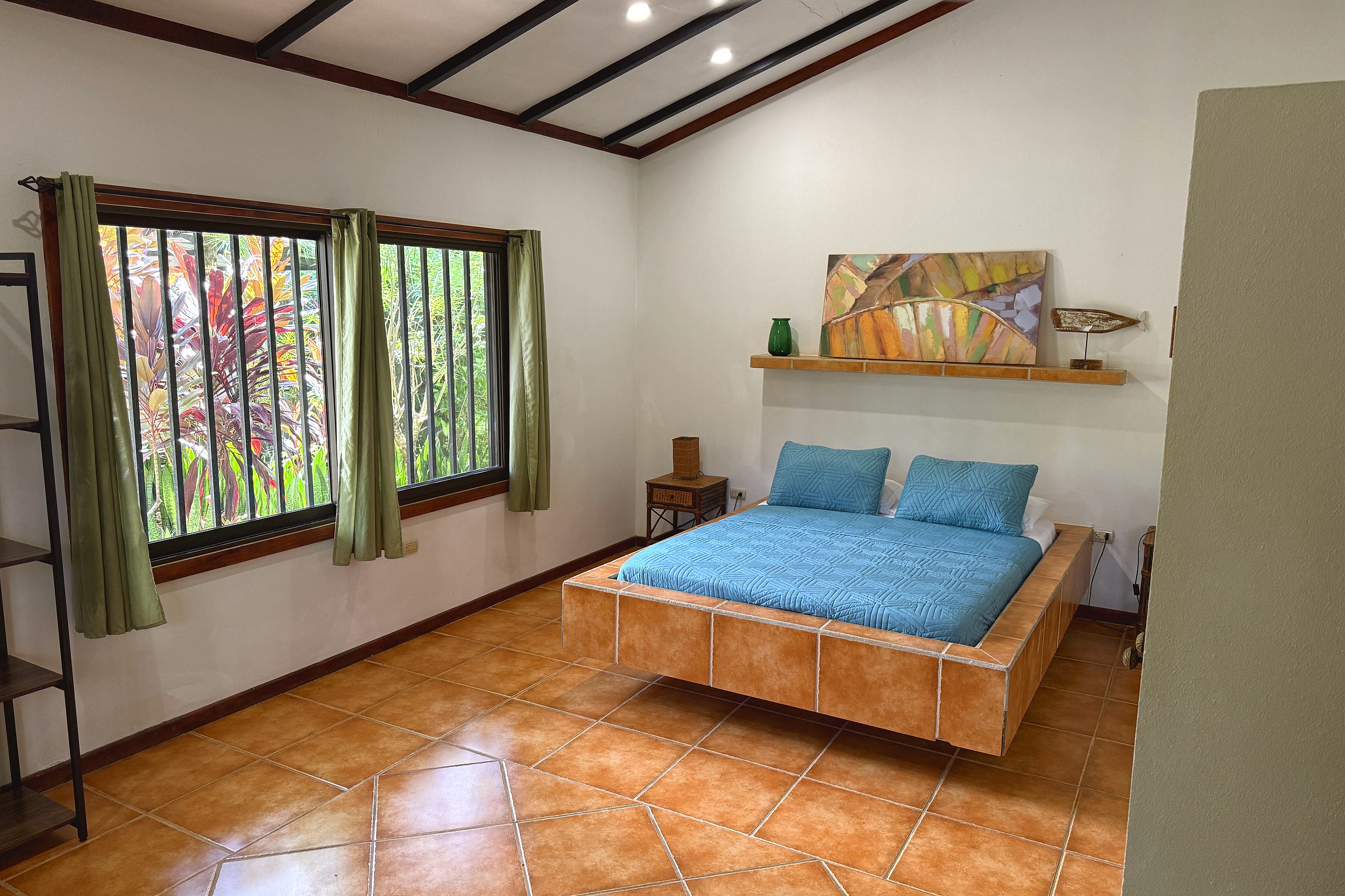 Tiled Platform Bed & Jungle View Jungle Sanctuary bedroom with tiled platform bed and jungle-view windows in Ojochal, Costa Rica.