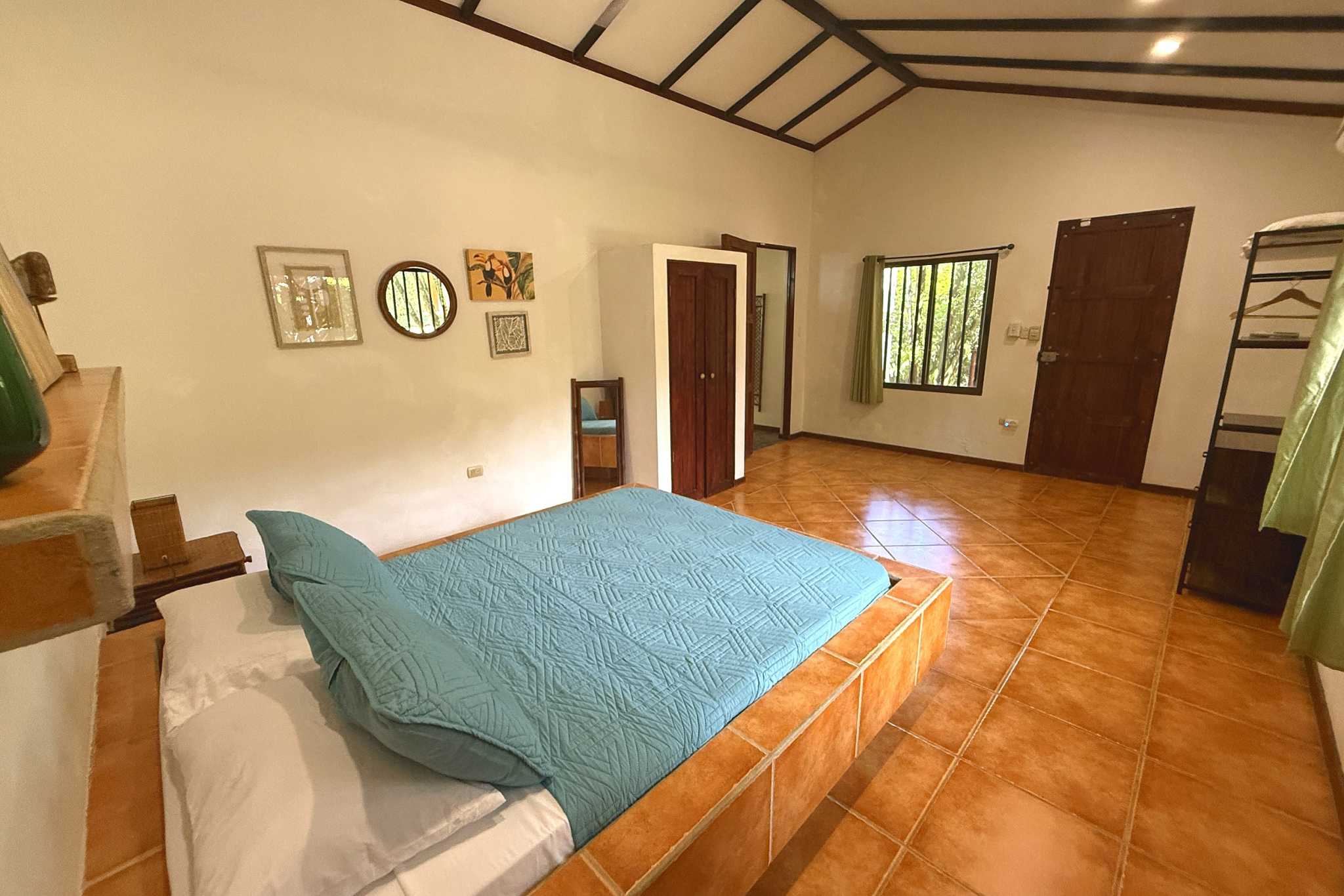 Cozy Guest Bedroom Jungle Sanctuary Retreat teal-bedded platform bed with tiled floor and wall art in Ojochal, Costa Rica