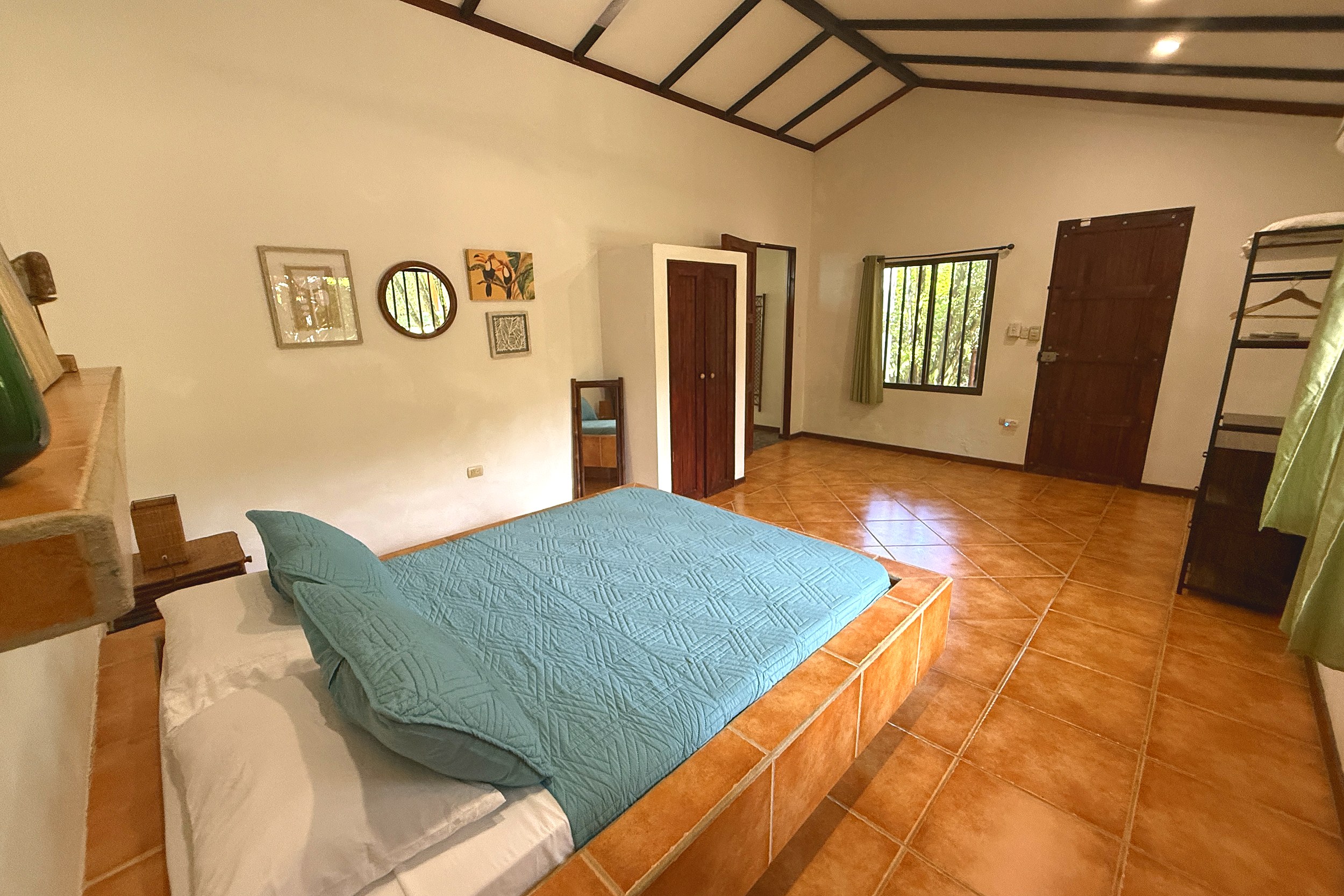 Cozy Guest Bedroom Jungle Sanctuary Retreat teal-bedded platform bed with tiled floor and wall art in Ojochal, Costa Rica