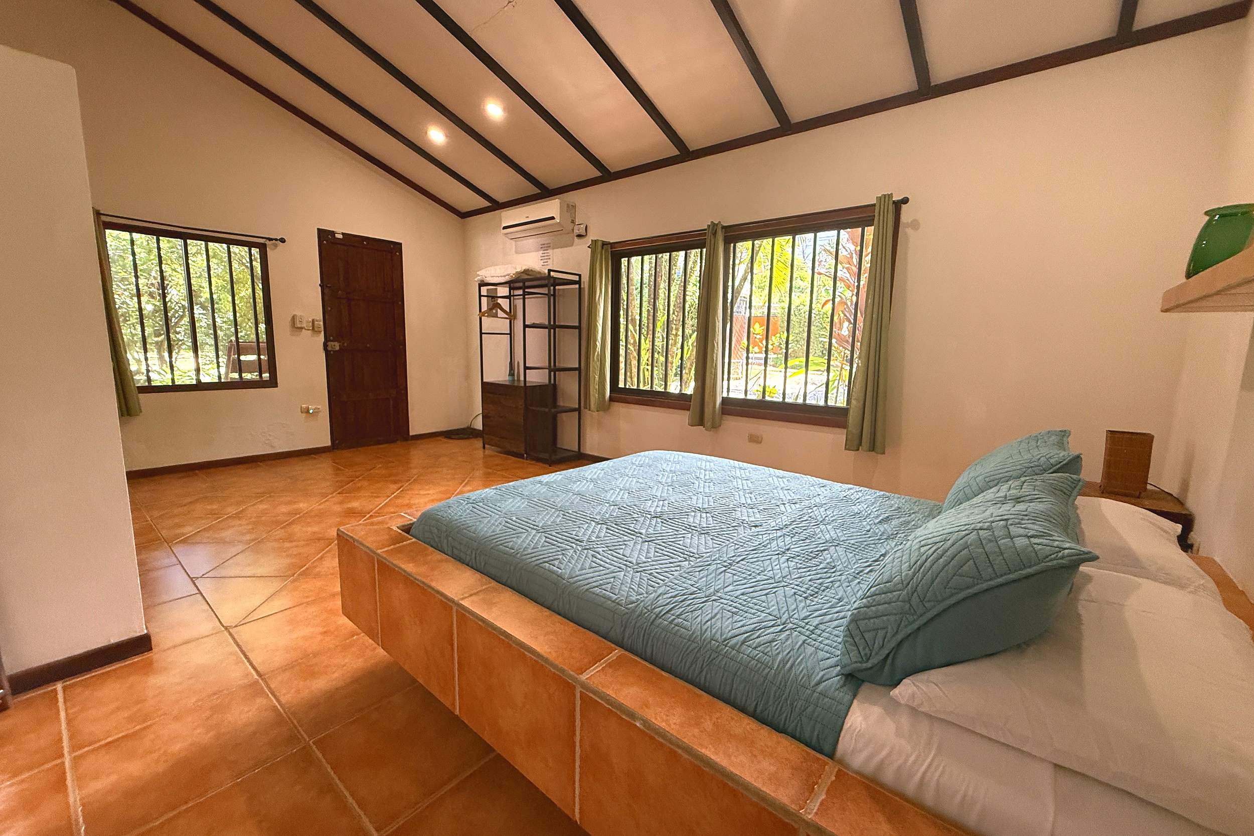 Tiled Platform Bed & Jungle Views Jungle Sanctuary bedroom with tiled bed platform, teal linens and jungle-view windows in Ojochal, Costa Rica
