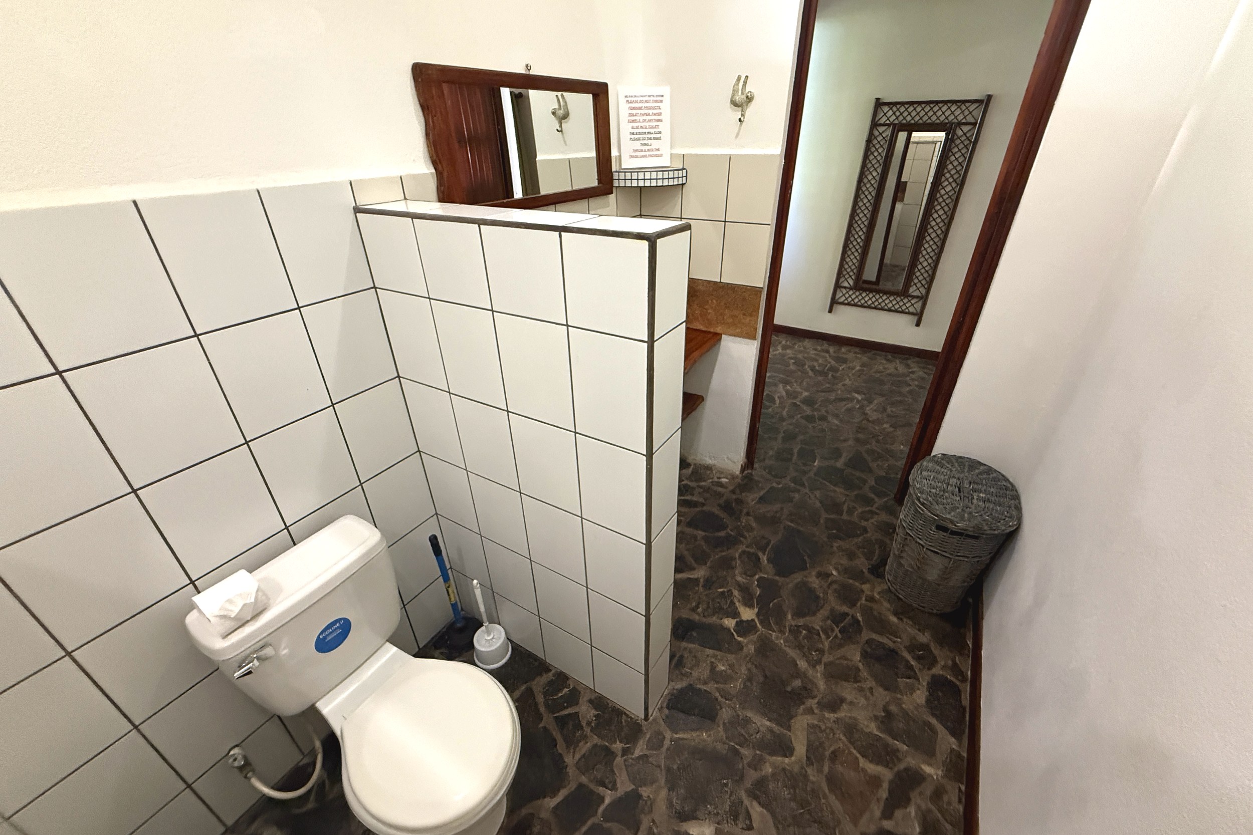 Tiled Guest Bathroom Serene Jungle Sanctuary tiled bathroom with toilet and stone floor hallway in Ojochal, Costa Rica