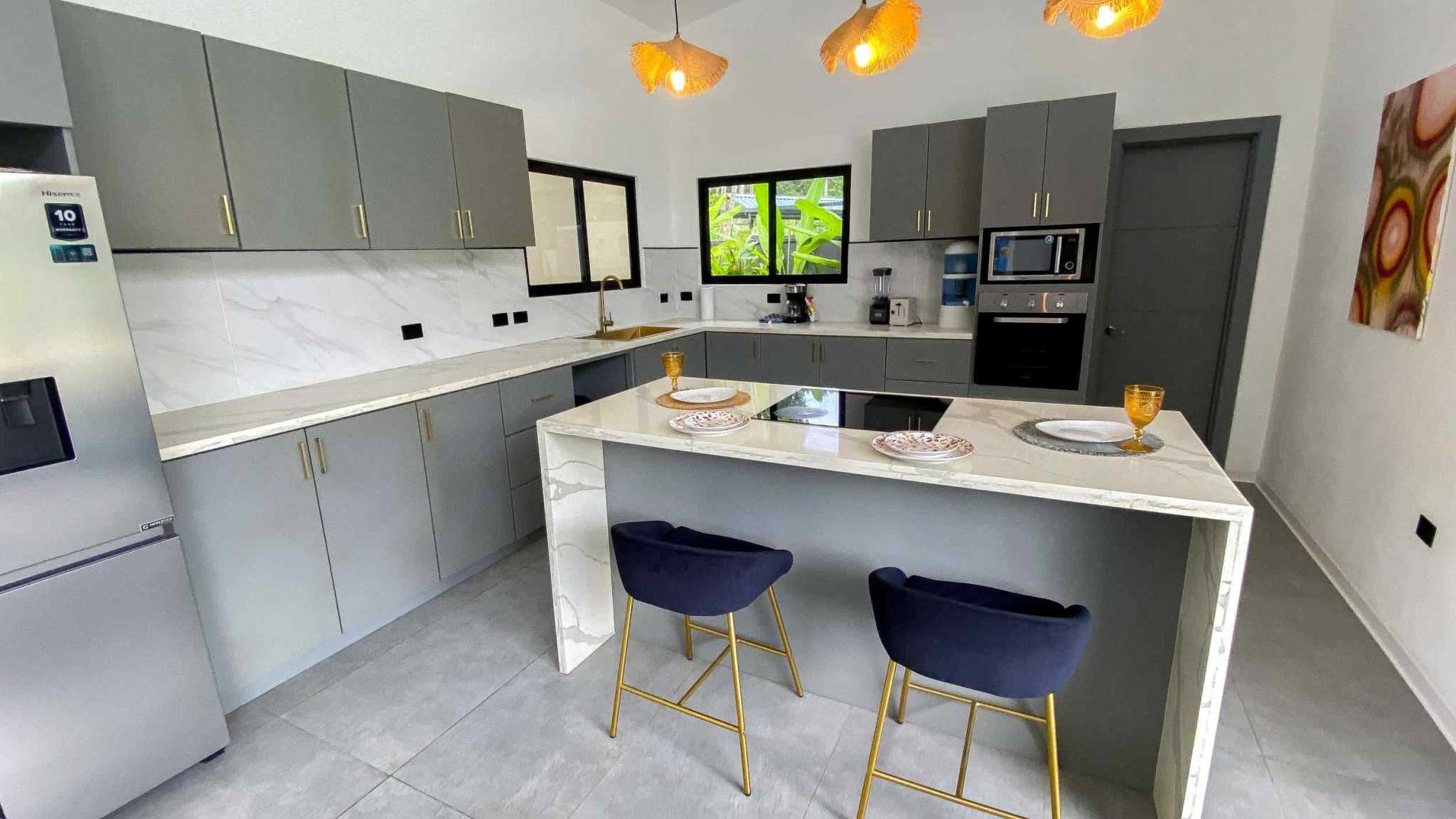 Resort-Style Home kitchen with island bar, gray cabinets and pendant lights in Uvita, Costa Rica