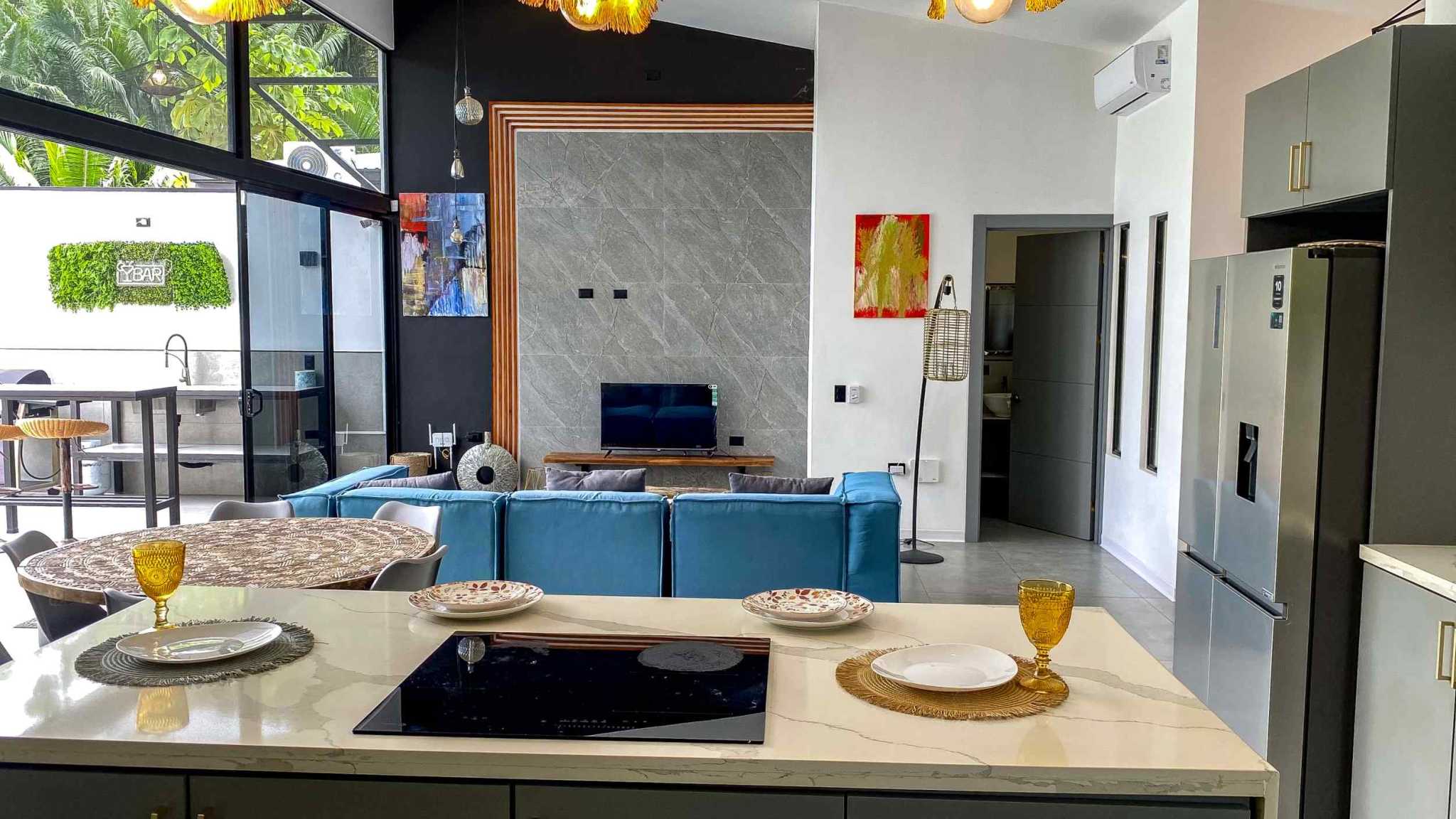 Resort-Style Home kitchen island and living room with blue sofa and marble wall in Uvita, Costa Rica
