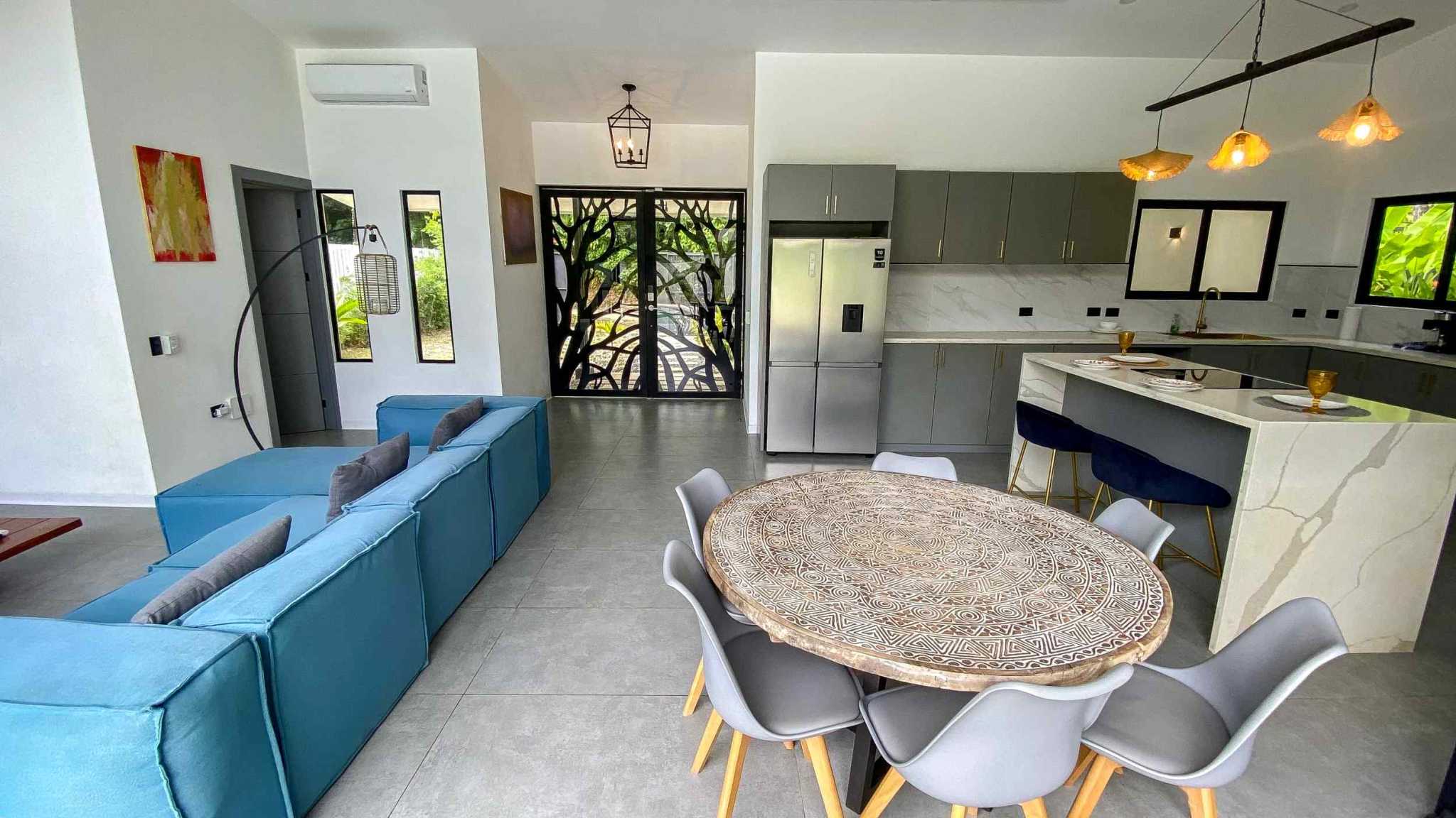 Resort-Style Home open living area, kitchen island, dining table and blue sofa in Uvita, Costa Rica