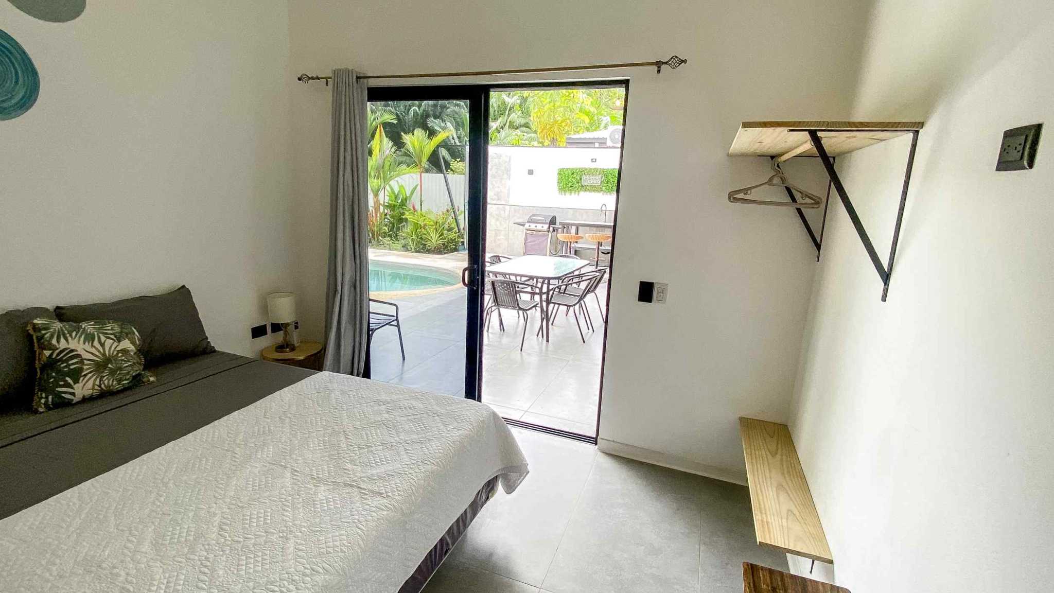 Resort-Style Home bedroom with sliding door to pool patio and tropical greenery in Uvita, Costa Rica