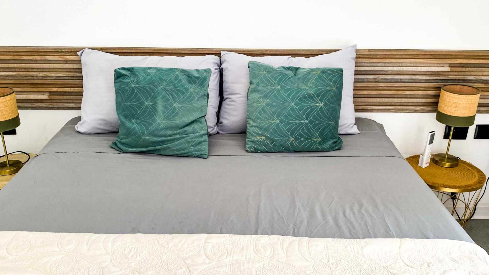 Resort-Style Home bed with wood slat headboard and green patterned pillows in Uvita, Costa Rica