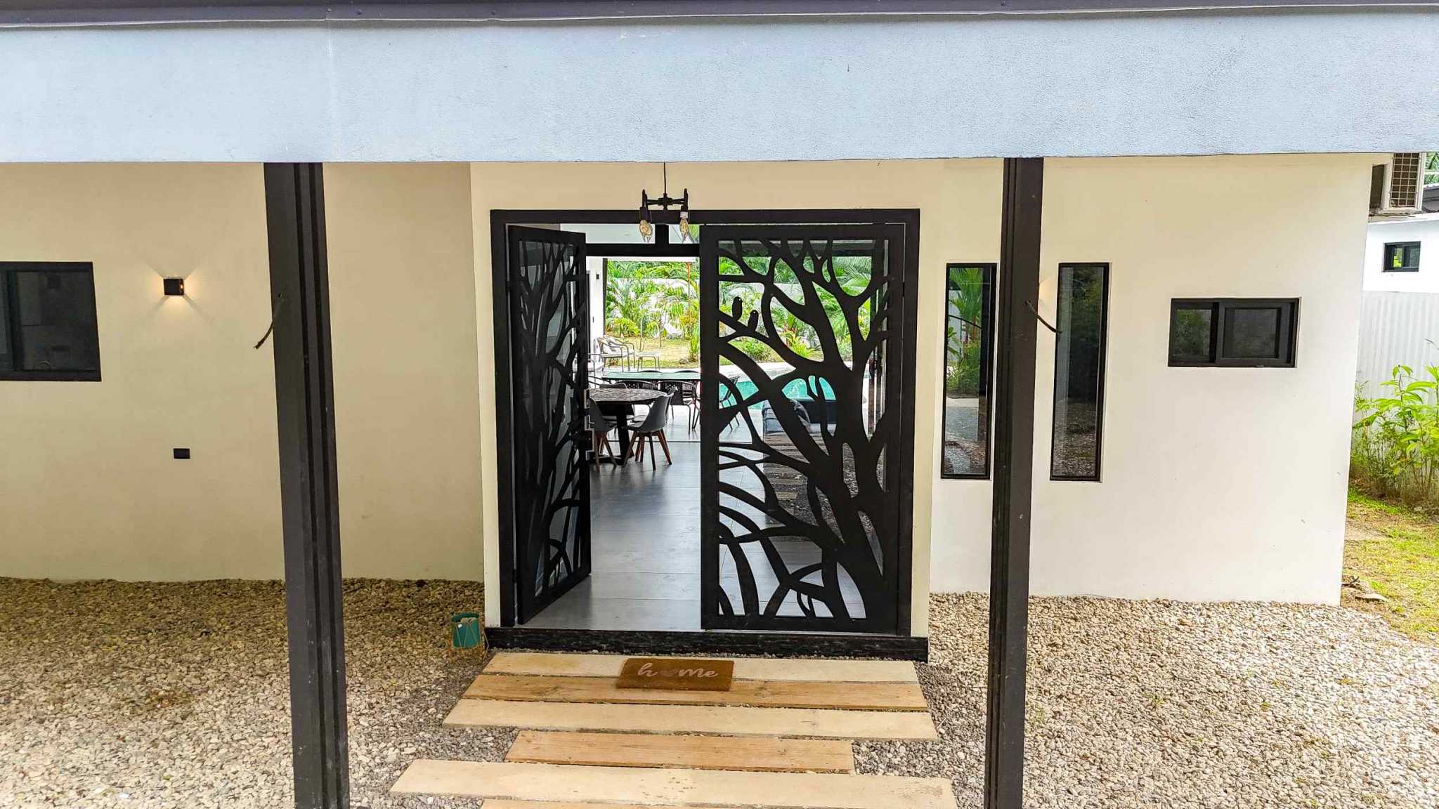 Resort-Style Home decorative iron double entrance doors open to pool and dining area in Uvita, Costa Rica