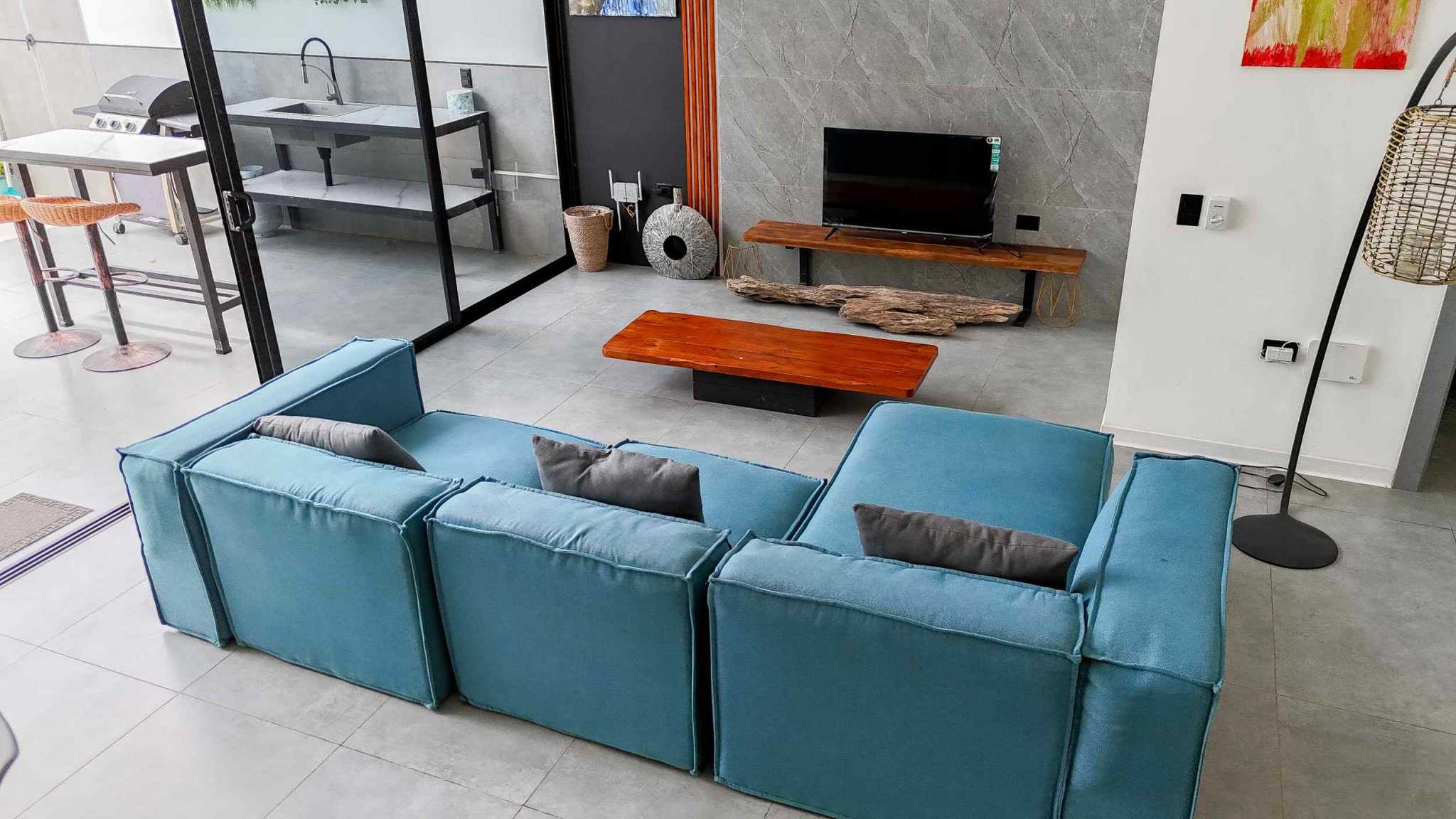 Resort-Style Home living room with teal sectional sofa, TV console and open kitchen in Uvita, Costa Rica
