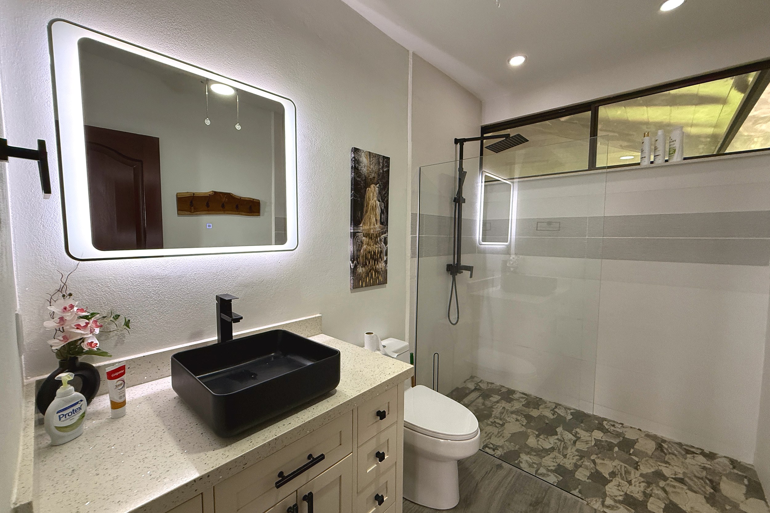 Modern Vanity & Glass Shower Guest Bathroom black vessel sink, lighted mirror, and glass shower in Costa Rica