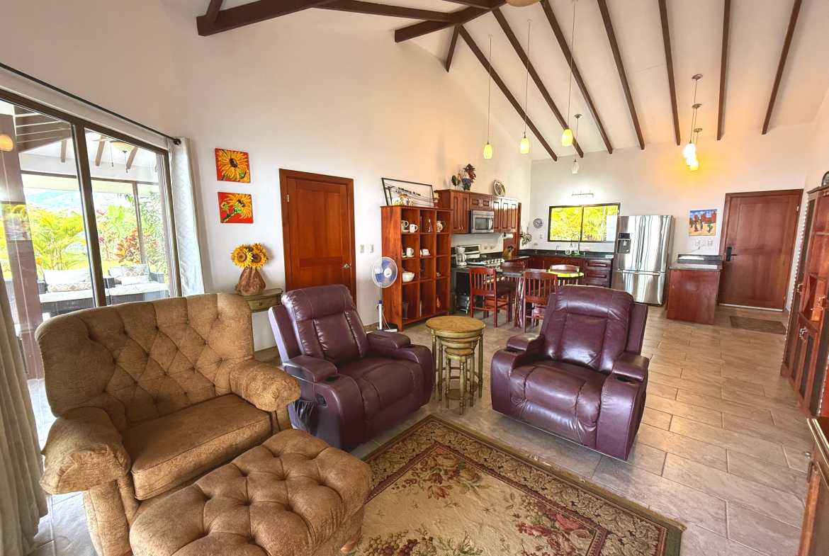Living room with leather recliners, vaulted ceiling, and glass doors opening to the terrace in Toucan Valley.