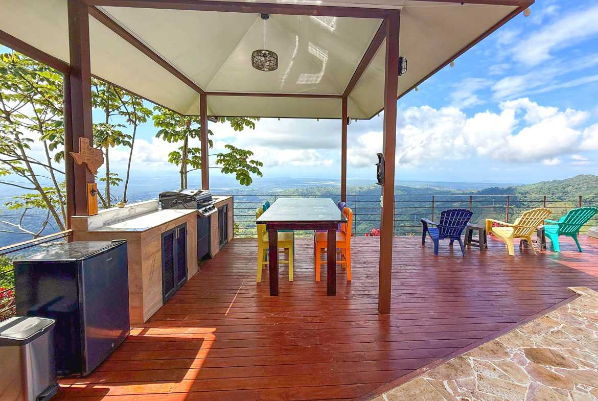 Covered terrace with outdoor sofa, pool deck, and mountain views in Toucan Valley, Costa Rica.