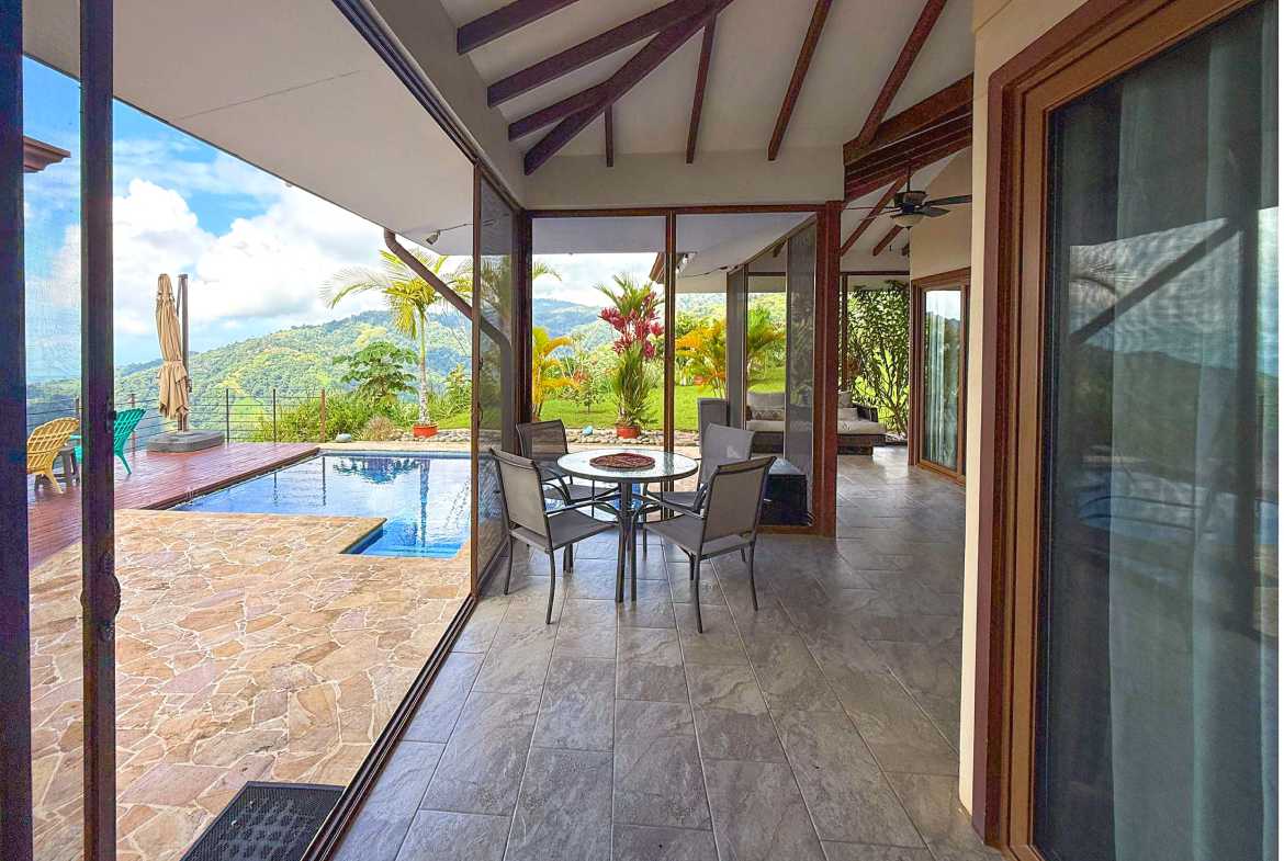 Covered terrace dining area opening to the pool and lush mountain views in Toucan Valley, Costa Rica.