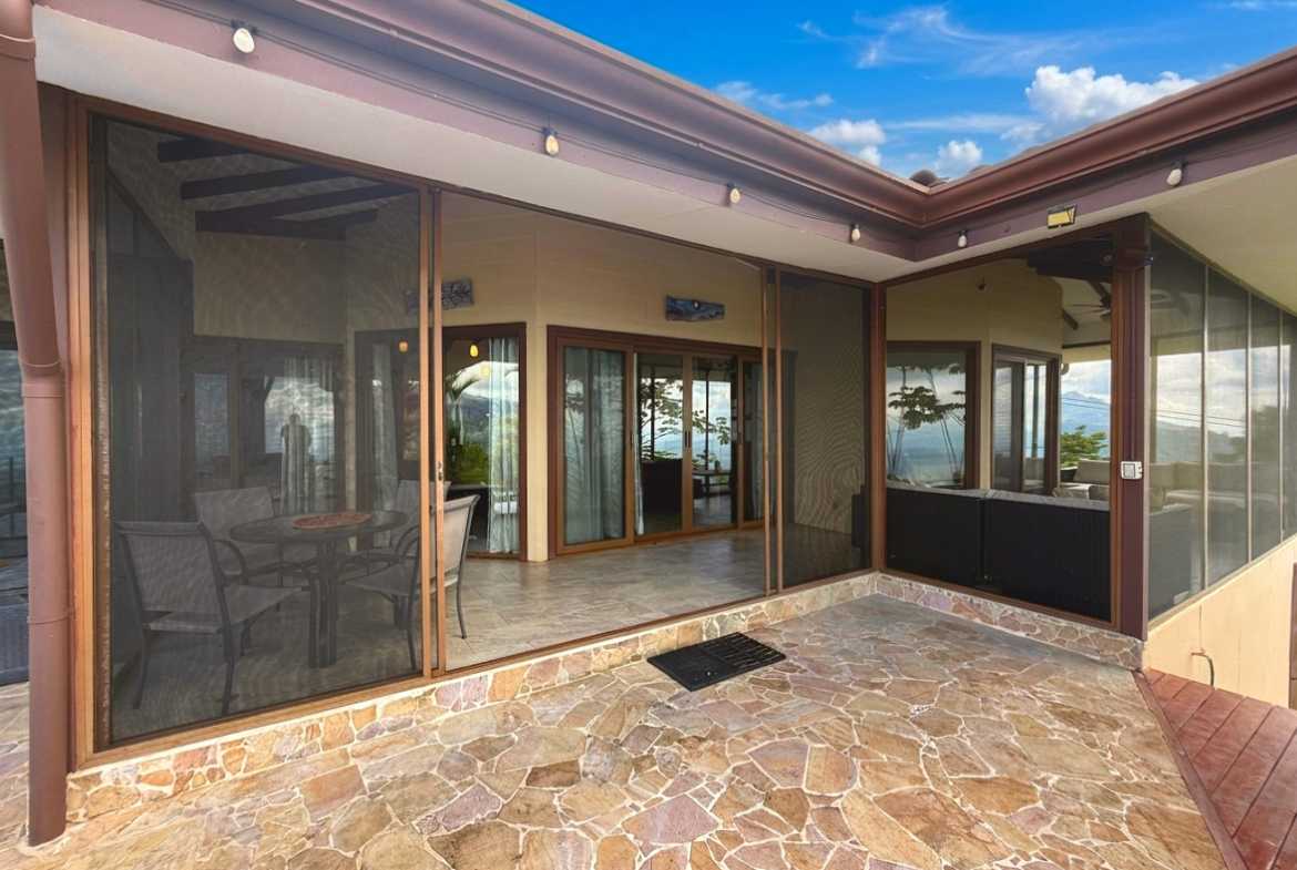 Covered flagstone patio with sliding screen doors and outdoor dining in Toucan Valley, Costa Rica.