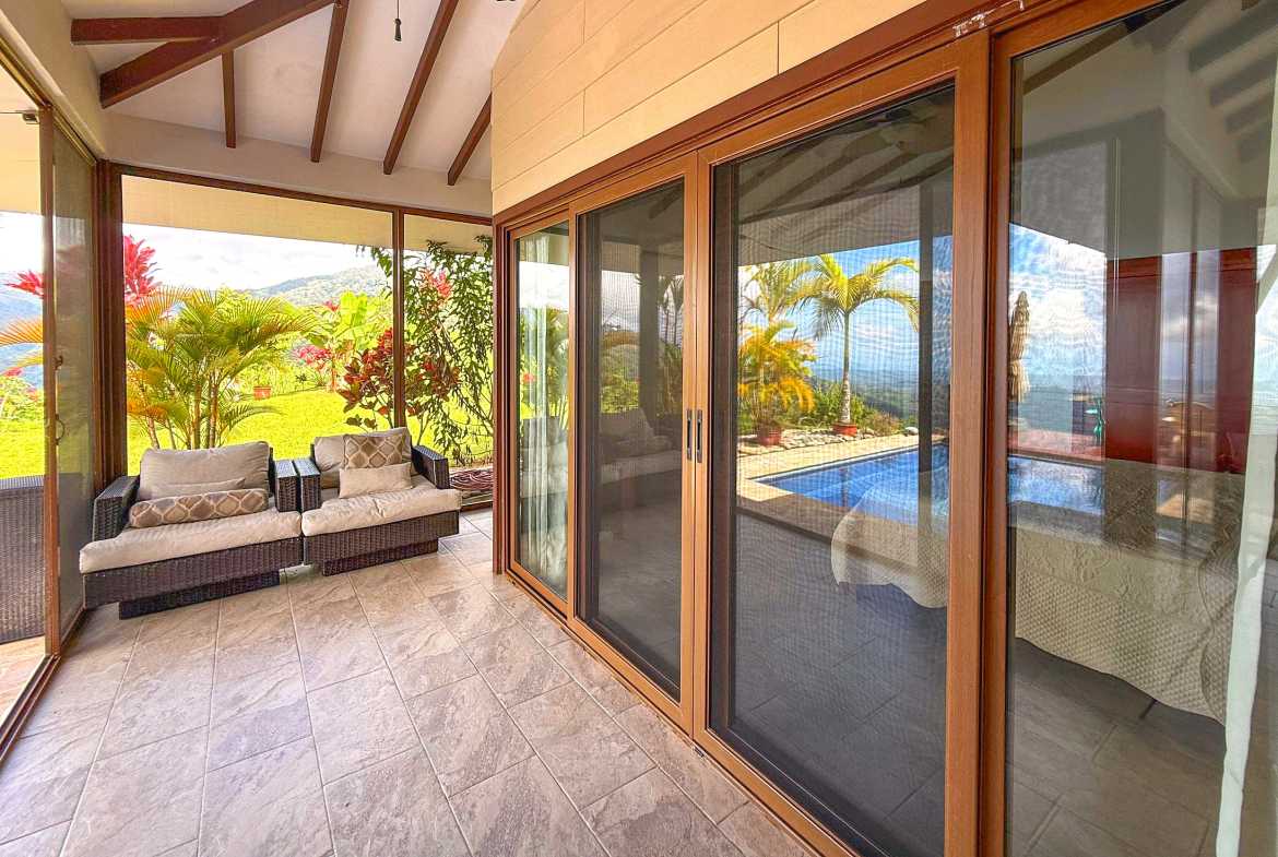 Tiled covered terrace with outdoor armchairs and large sliding doors in Toucan Valley, Costa Rica.