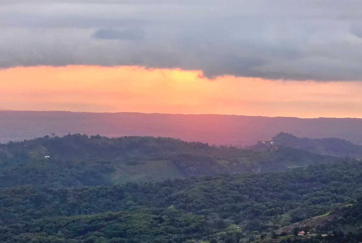 Golden sunset glowing over lush mountain ridges and the Osa Peninsula in Toucan Valley, Costa Rica.